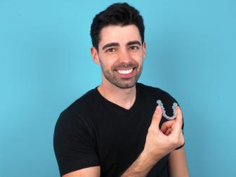 Mann hält lächelnd einen Aligner