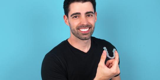 Mann hält lächelnd einen Aligner