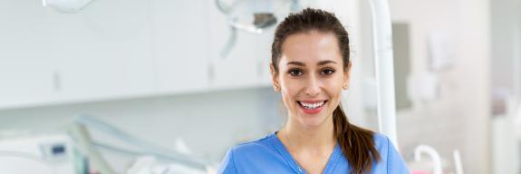 Junge MFA steht lächelnd in der Praxis