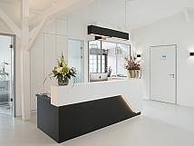 Schwarz-weißer Rezeptionstisch mit Computer und Blumen