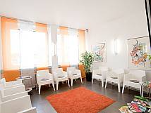 Modernes orange-weißes Wartezimmer mit Plastikstühlen und flauschigem Teppich